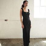 Woman wearing a black evening gown in a minimal indoor setting