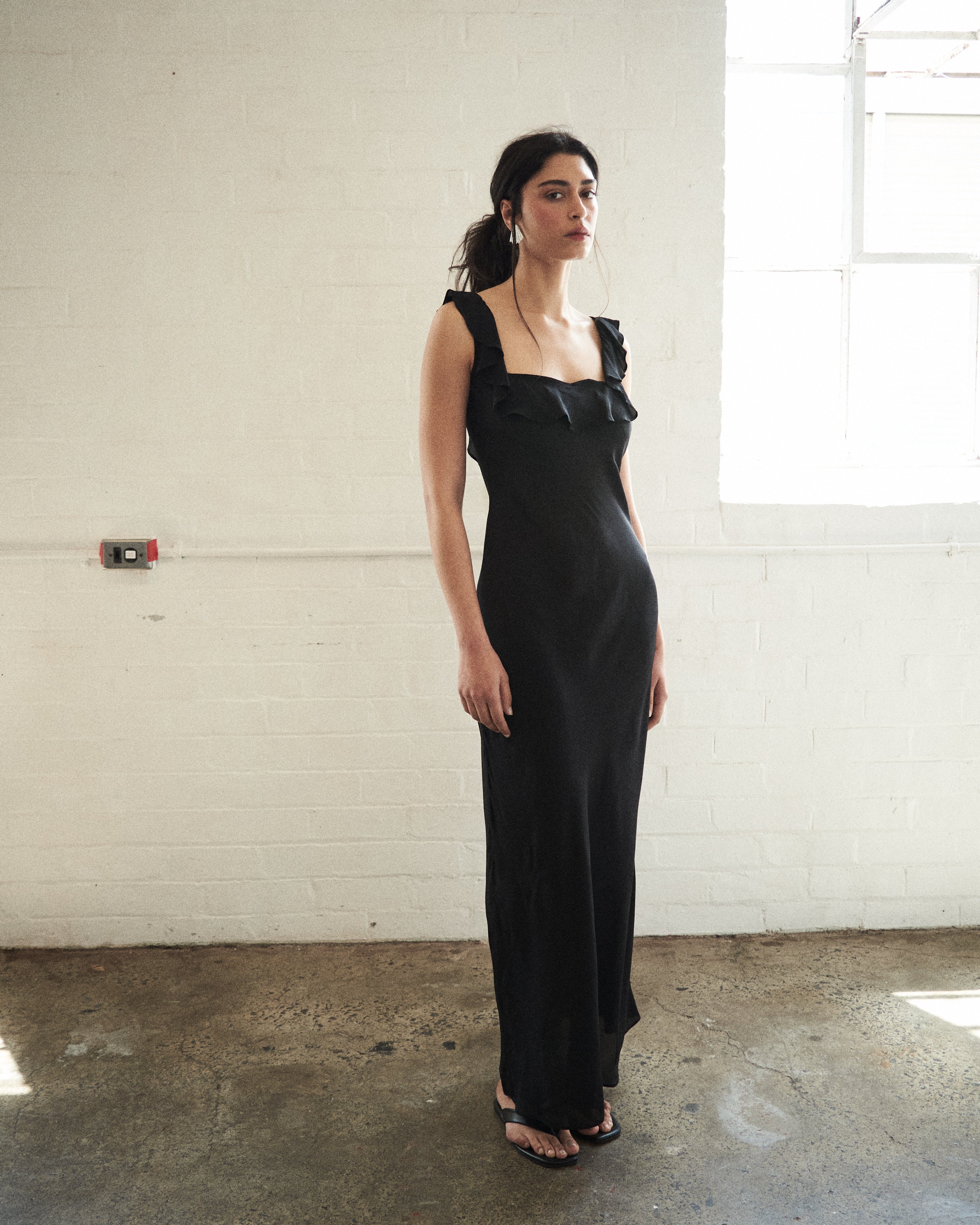Woman wearing a black evening gown in a minimal indoor setting