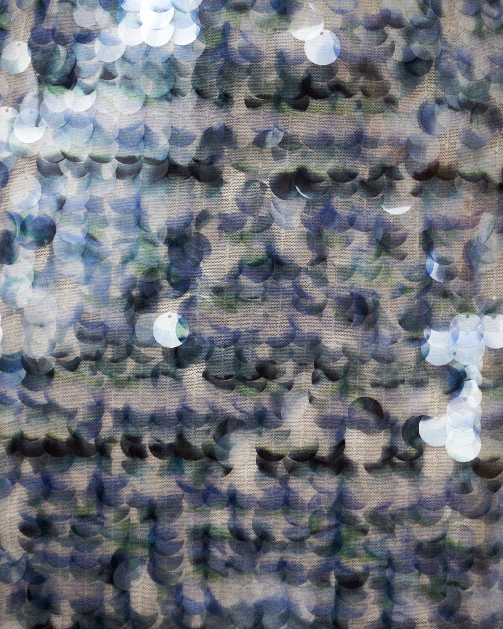 Close-up of a sequin fabric in blue, green, and beige.