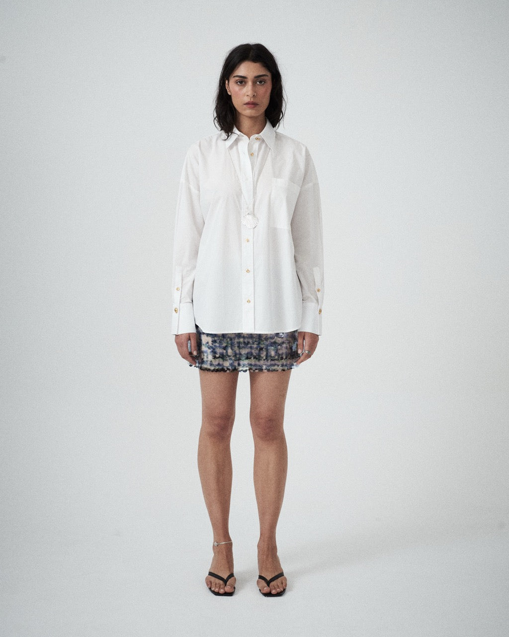Woman wearing a white shirt and sequins mini skirt on a white background