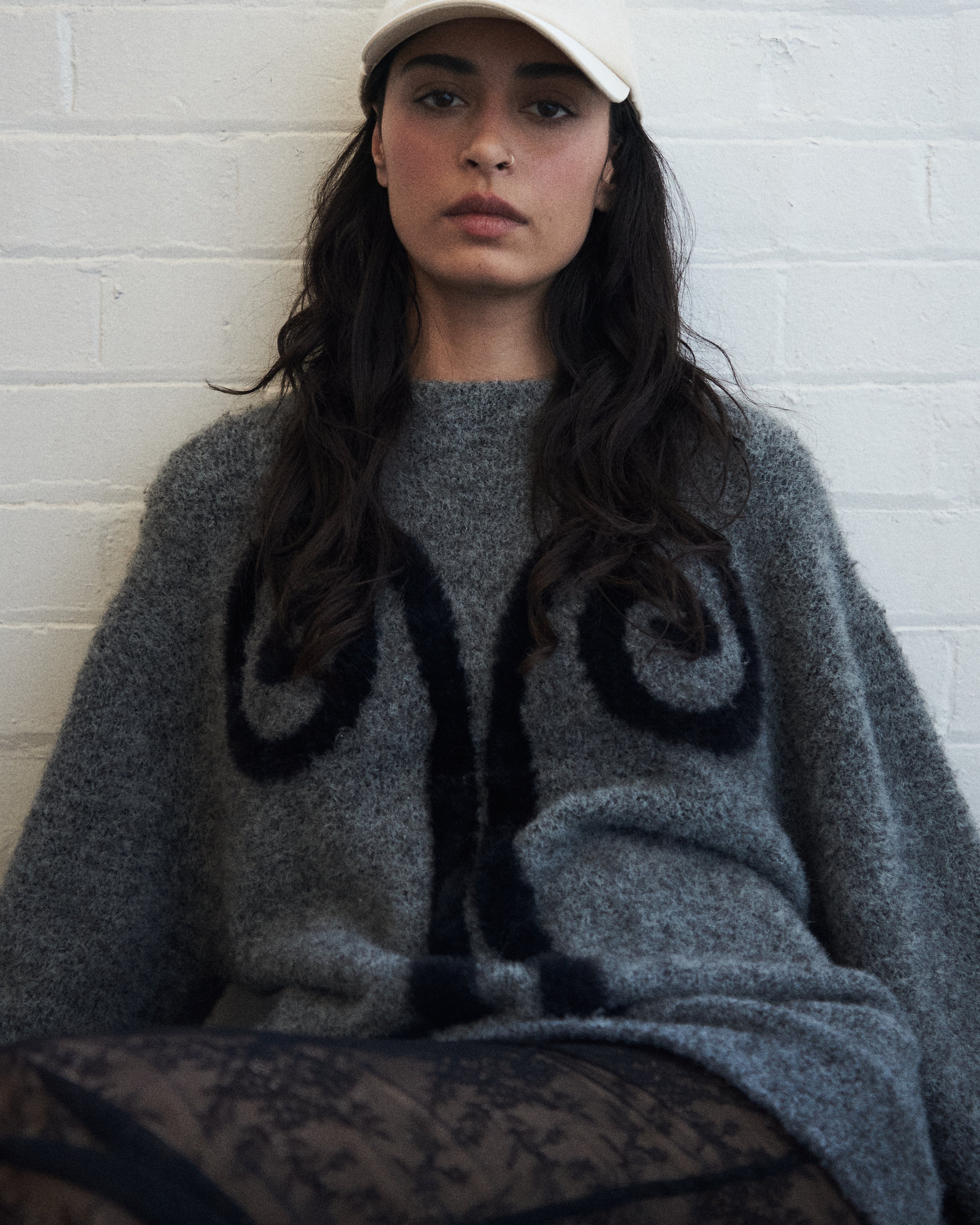 Editorial mood shot of the VARNA Maris Knit Top in charcoal — oversized alpaca-wool sweater with abstract motif and balloon sleeves.