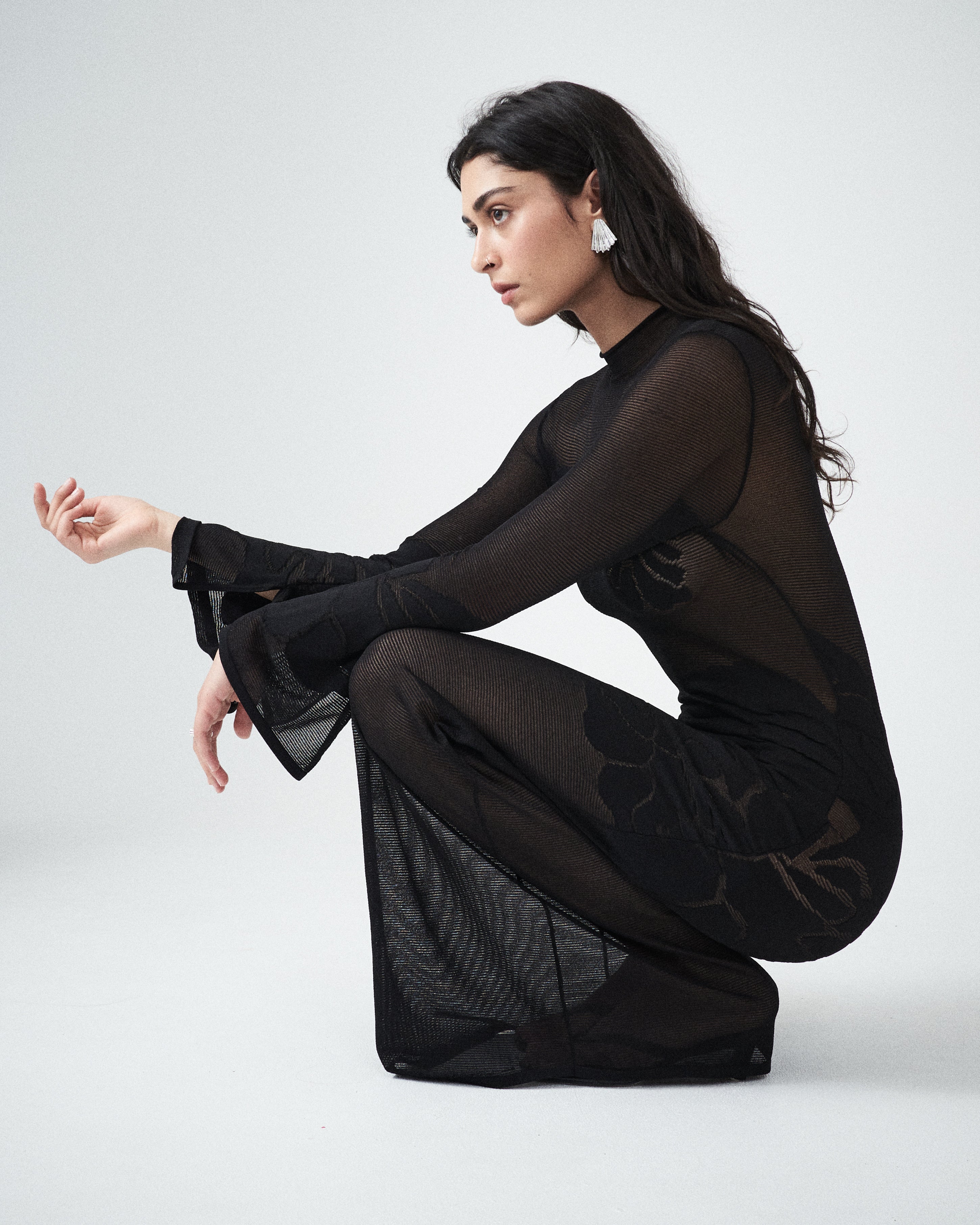 Sheer black knit designer maxi dress by VARNA, styled with refined accessories.