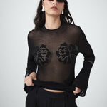 Sheer black knit designer top by VARNA styled with tailored trousers.