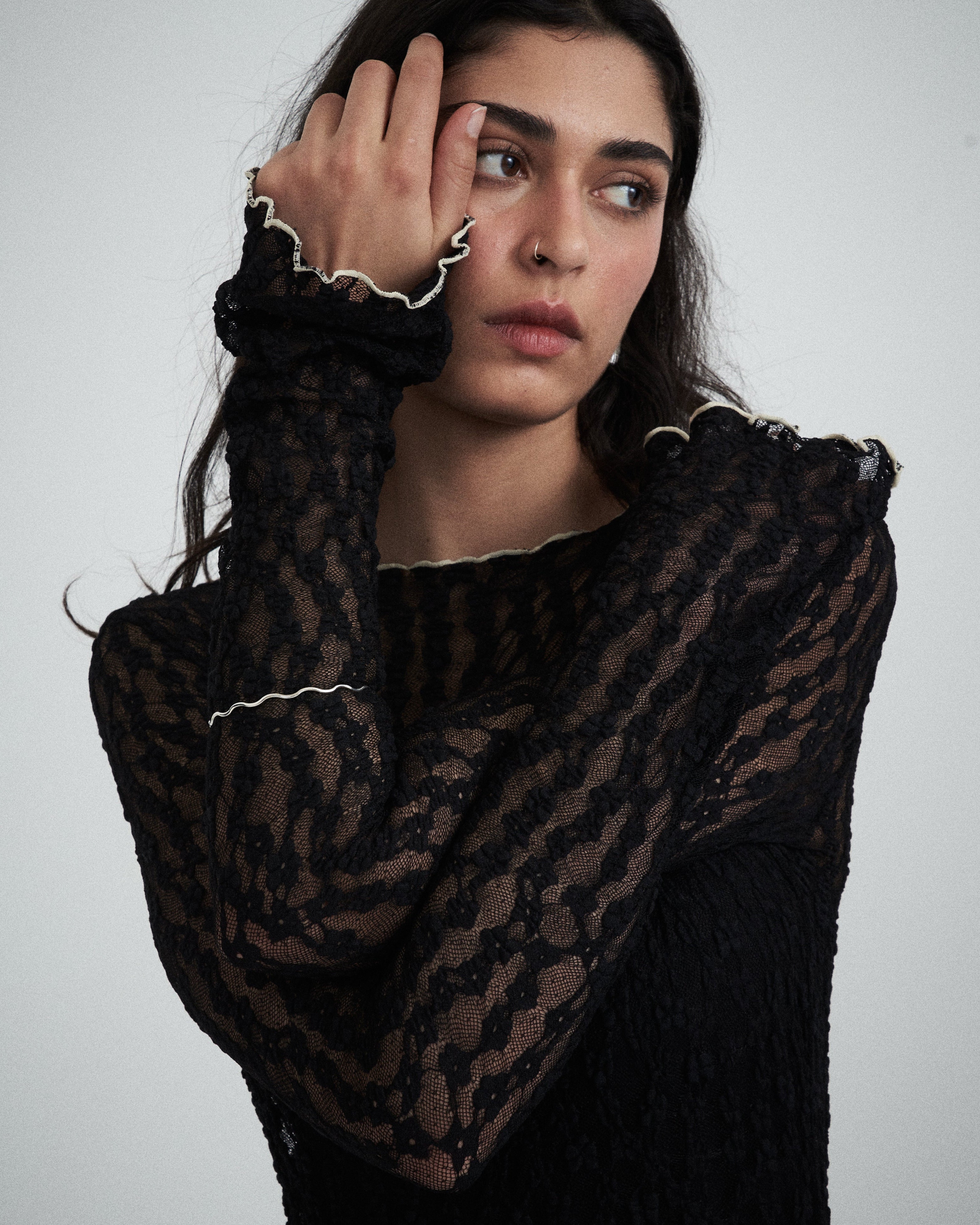 Editorial close-up of the VARNA Cecil Lace Top in black — delicate floral lace with contrast trim and romantic sheer texture.