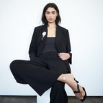 Editorial mood image of the VARNA Enrica Relaxed Tailored Pant in black — designer relaxed trouser styled with quiet sophistication.