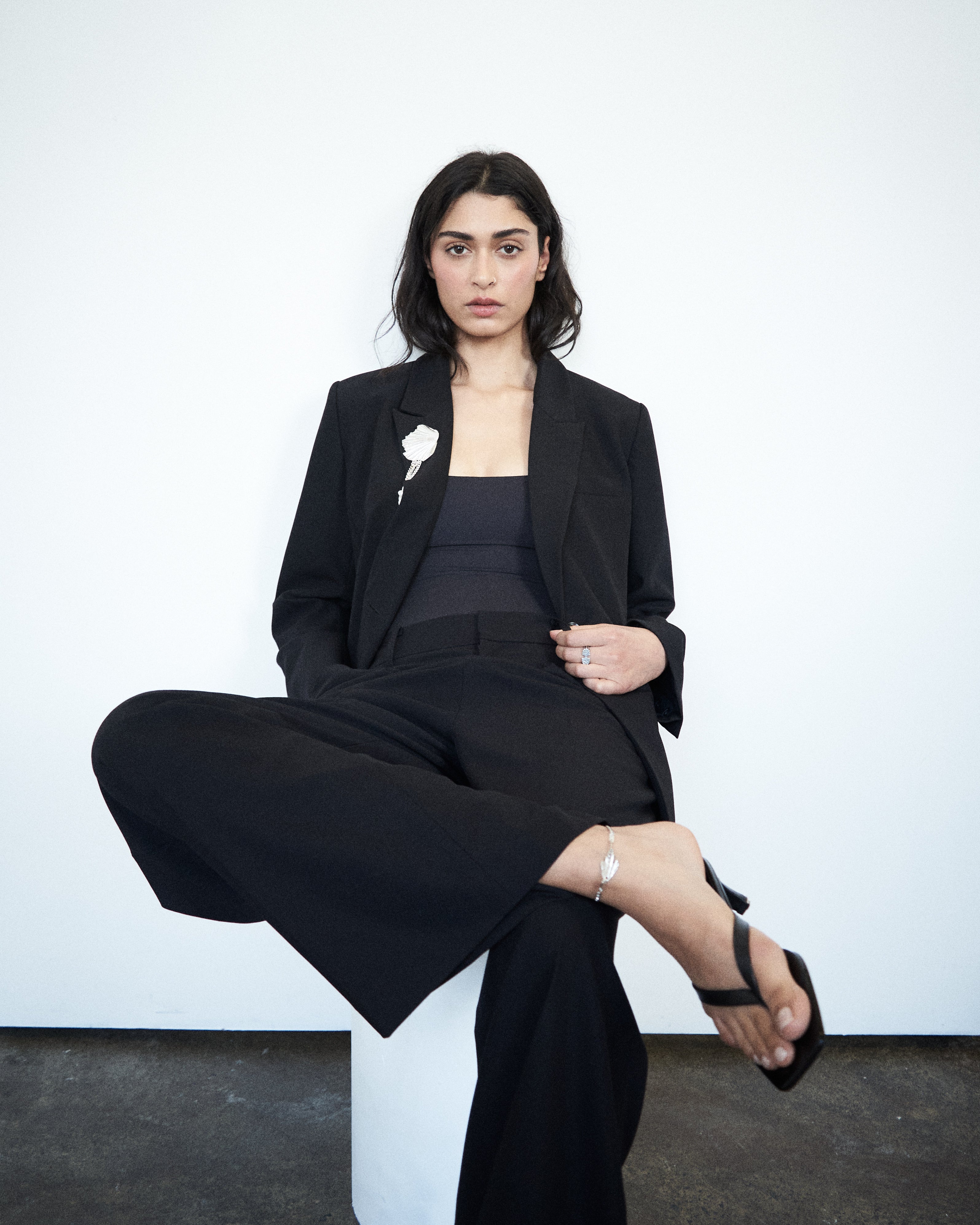 Editorial mood image of the VARNA Enrica Relaxed Tailored Pant in black — designer relaxed trouser styled with quiet sophistication.