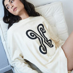 Designer oversized cotton sweater by VARNA with printed emblem in ivory.
