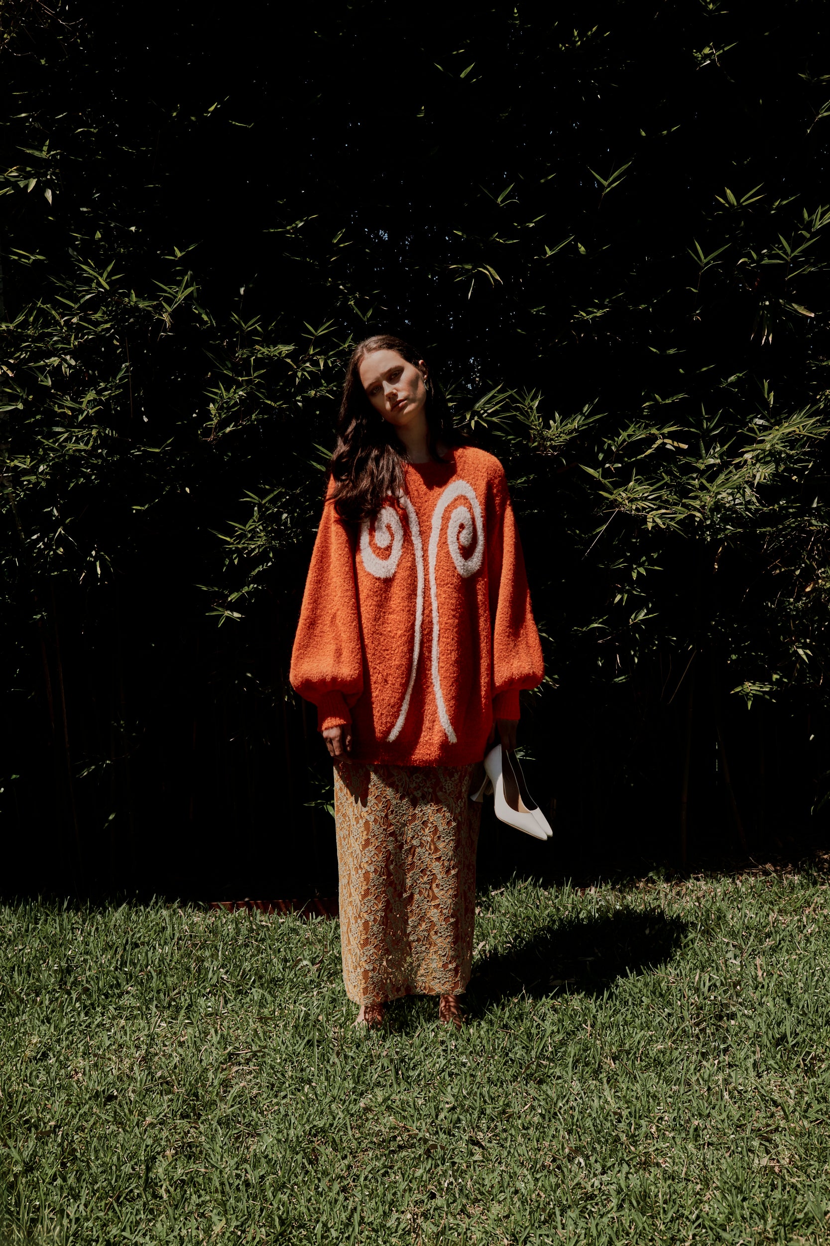 Editorial mood shot of the VARNA Lucienne Maxi Lace Skirt in tangerine — designer floral lace skirt with scalloped hem and fluid silhouette.