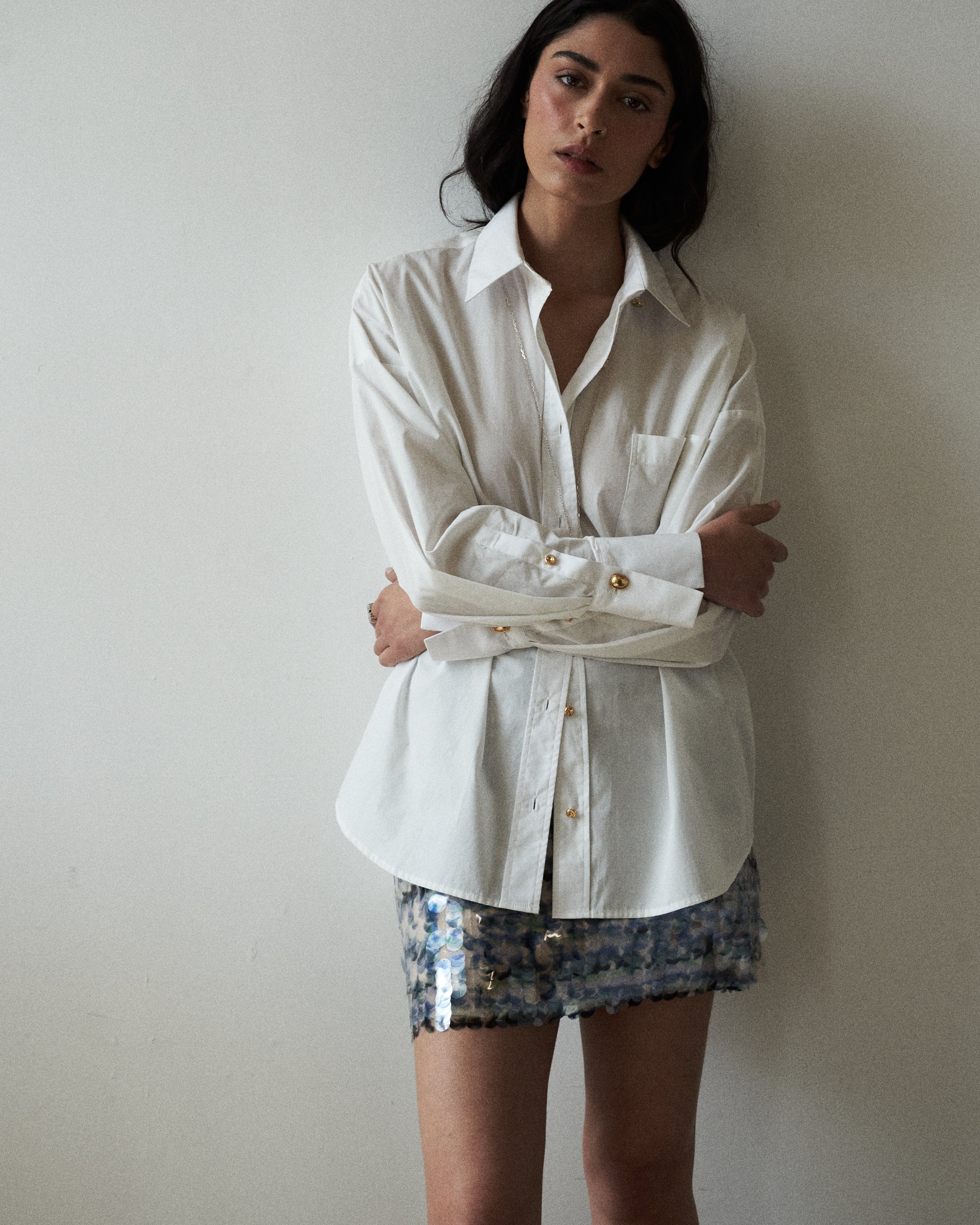 Editorial mood shot of the VARNA Rhea Shirt — designer white cotton button-down with gold-tone buttons and relaxed tailoring.