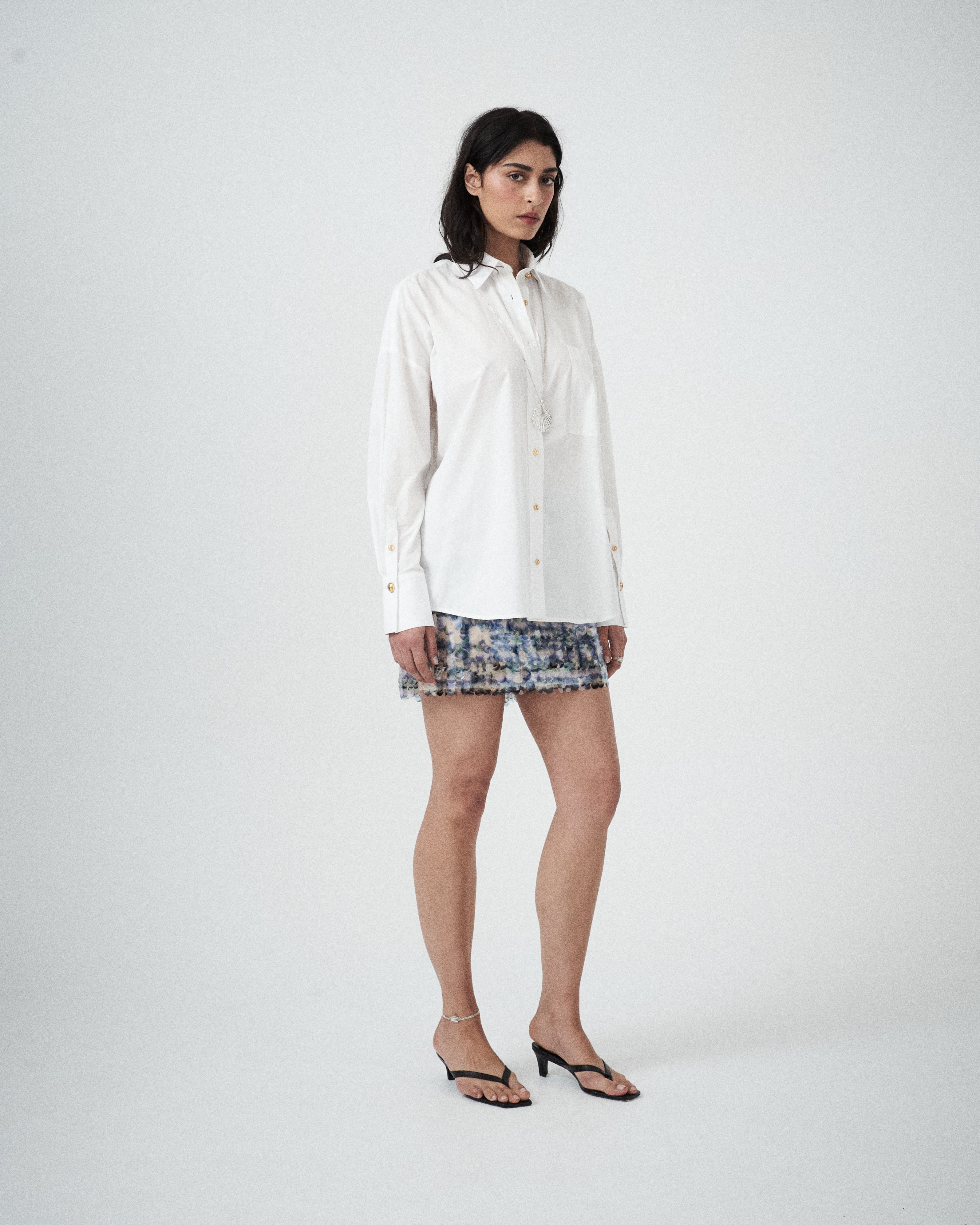 Three-quarter view of designer white cotton shirt by VARNA showing structured collar, relaxed silhouette, and soft drape.
