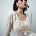 Editorial close-up of the VARNA Lucienne Ruffle Lace Maxi Dress in milk — delicate floral lace with ruffled neckline.