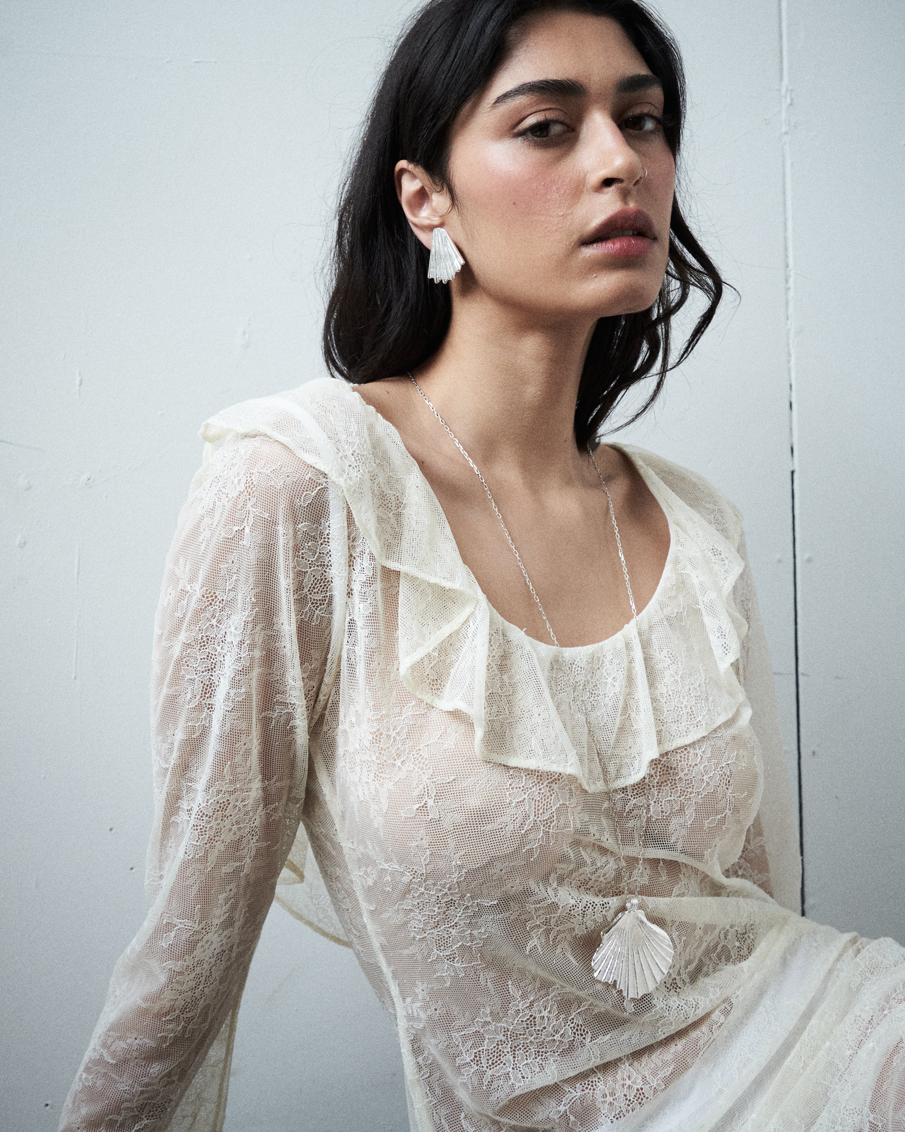 Editorial close-up of the VARNA Lucienne Ruffle Lace Maxi Dress in milk — delicate floral lace with ruffled neckline.
