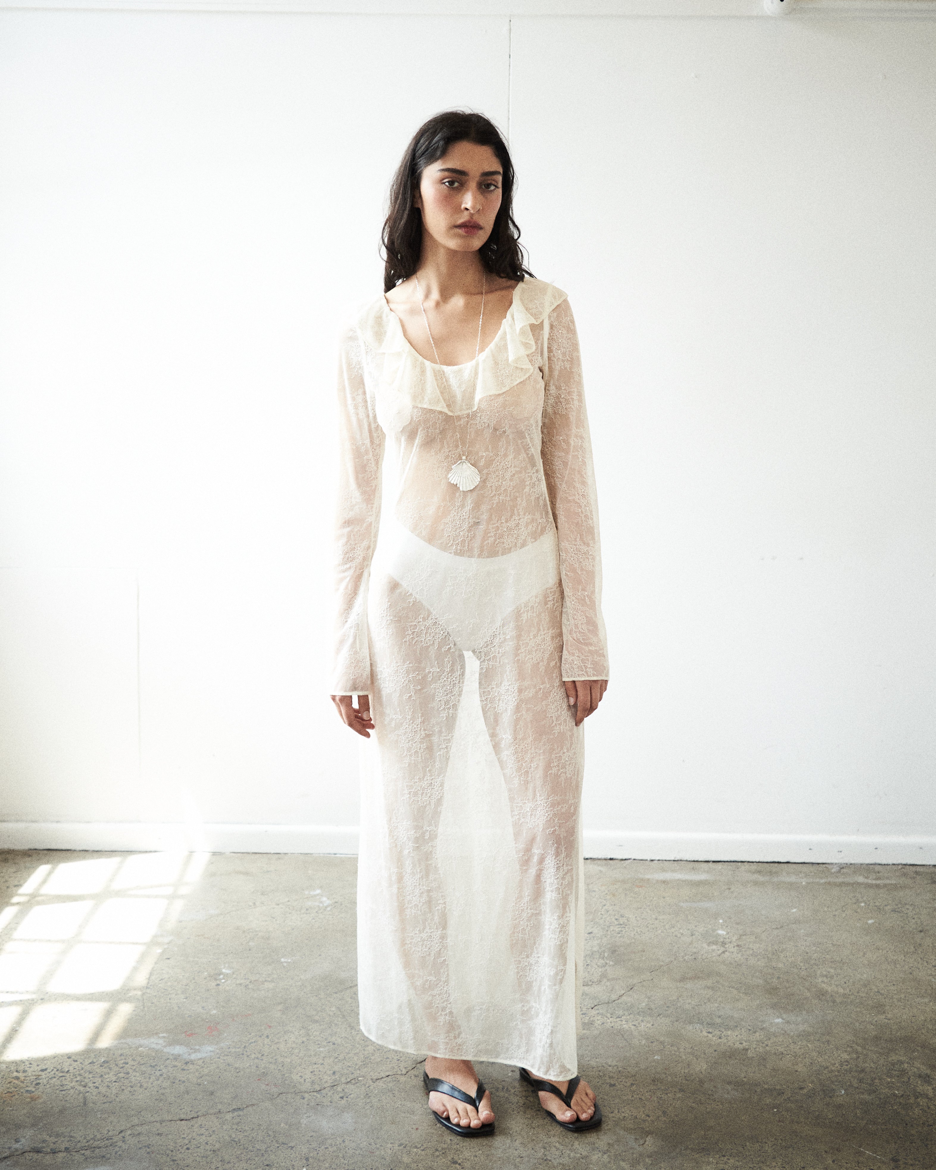 Editorial close-up of the VARNA Lucienne Ruffle Lace Maxi Dress in milk — delicate floral lace with ruffled neckline
