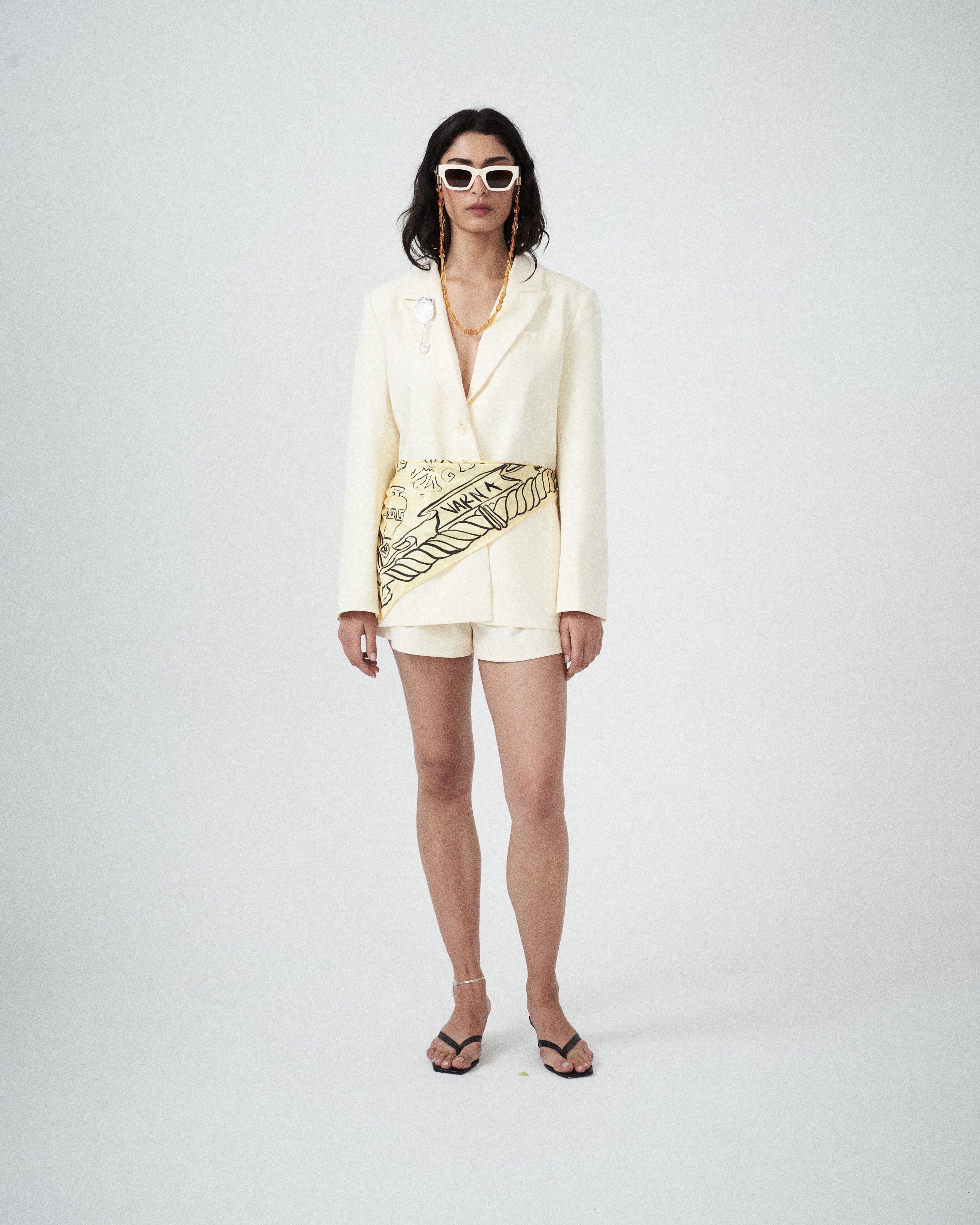 Woman wearing a cream-colored blazer with matching shorts on a white background