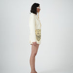 Woman side view wearing a cream-colored outfit with matching tailored shorts 