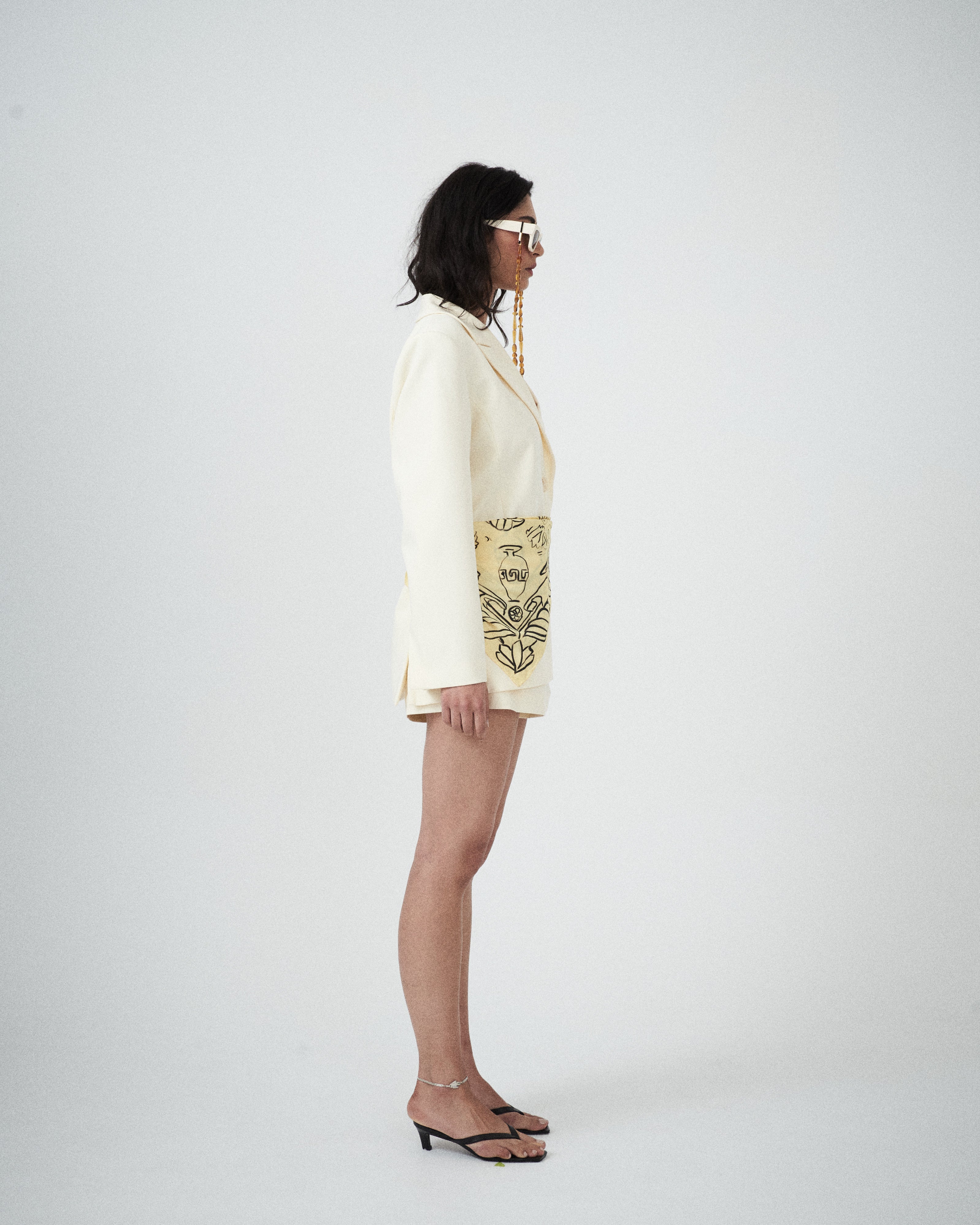 Woman side view wearing a cream-colored outfit with matching tailored shorts 