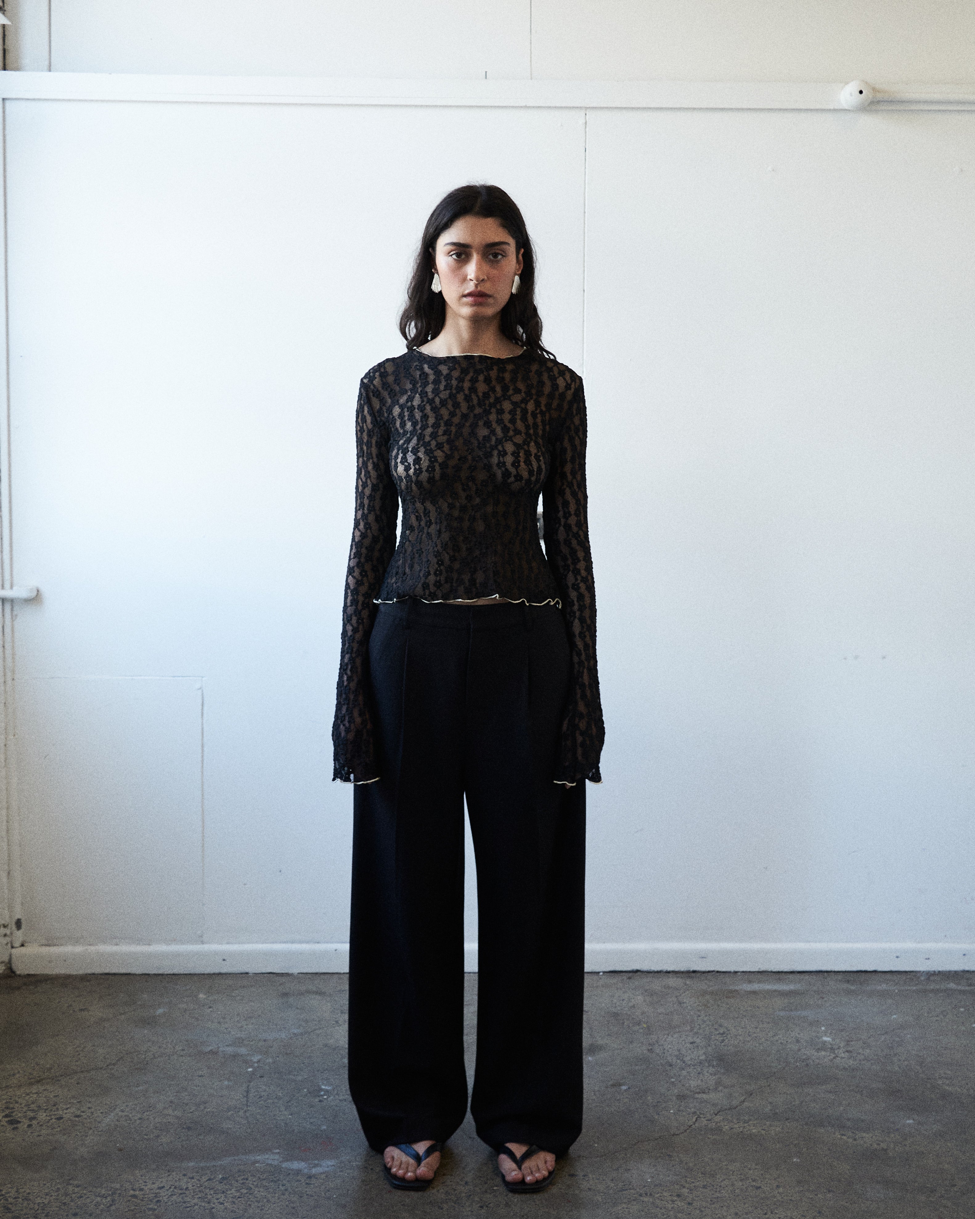 Designer black lace top by VARNA with scalloped hem and flared cuffs.