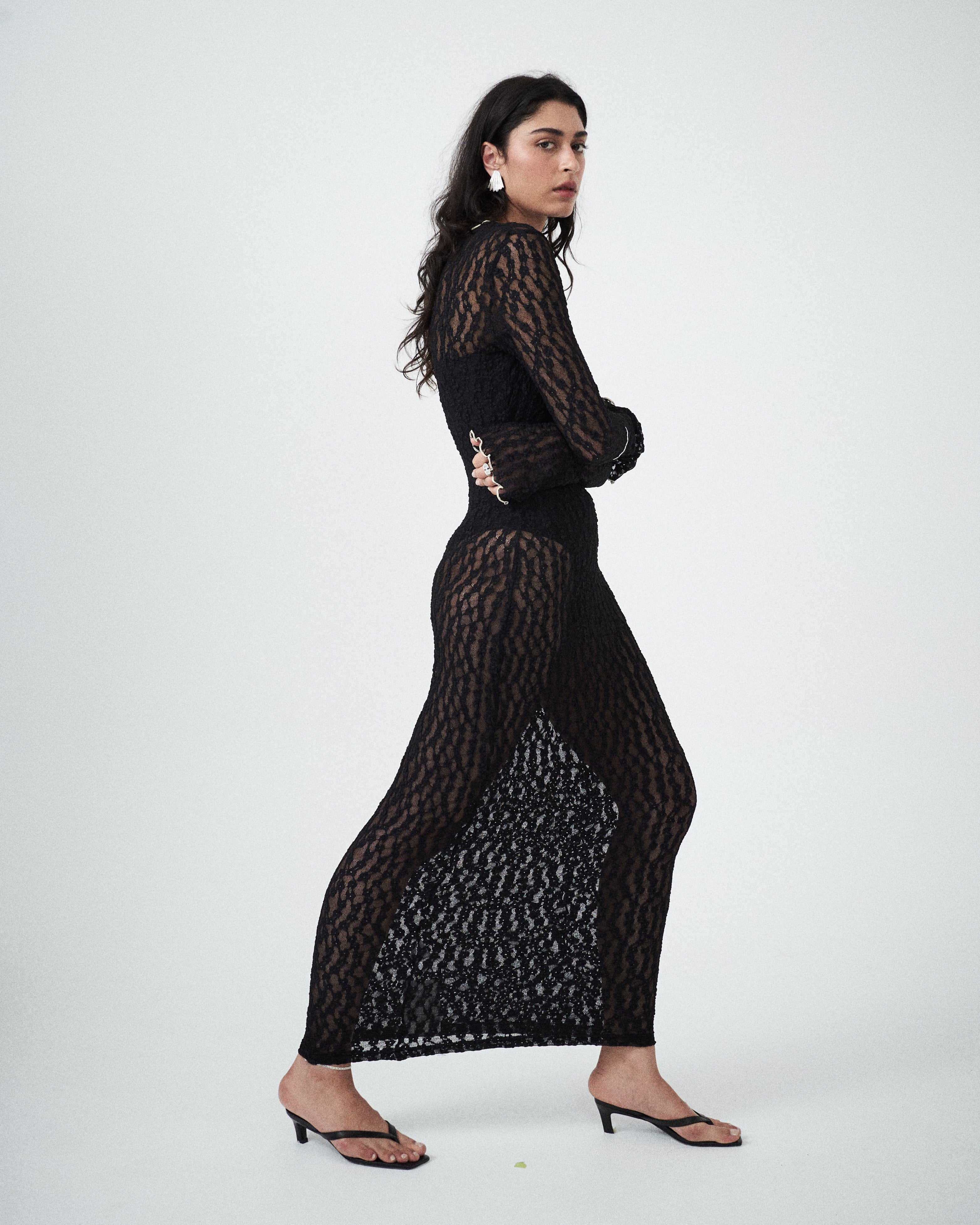 editorial shot of the VARNA Cecil Maxi Dress in sheer black lace — a bold, feminine evening statement.
