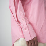 Close-up of a pink shirt cuff on a plain background