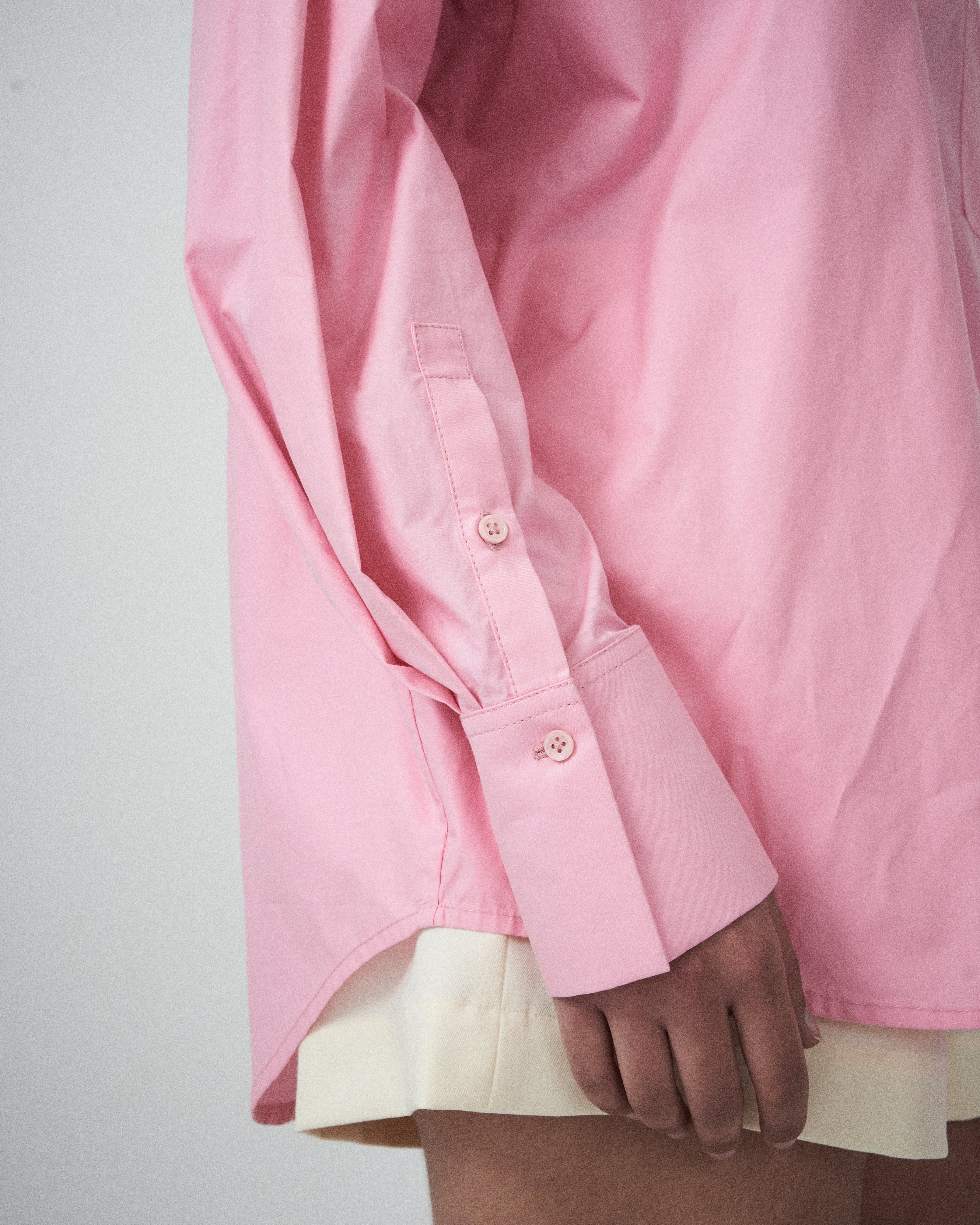 Close-up of a pink shirt cuff on a plain background