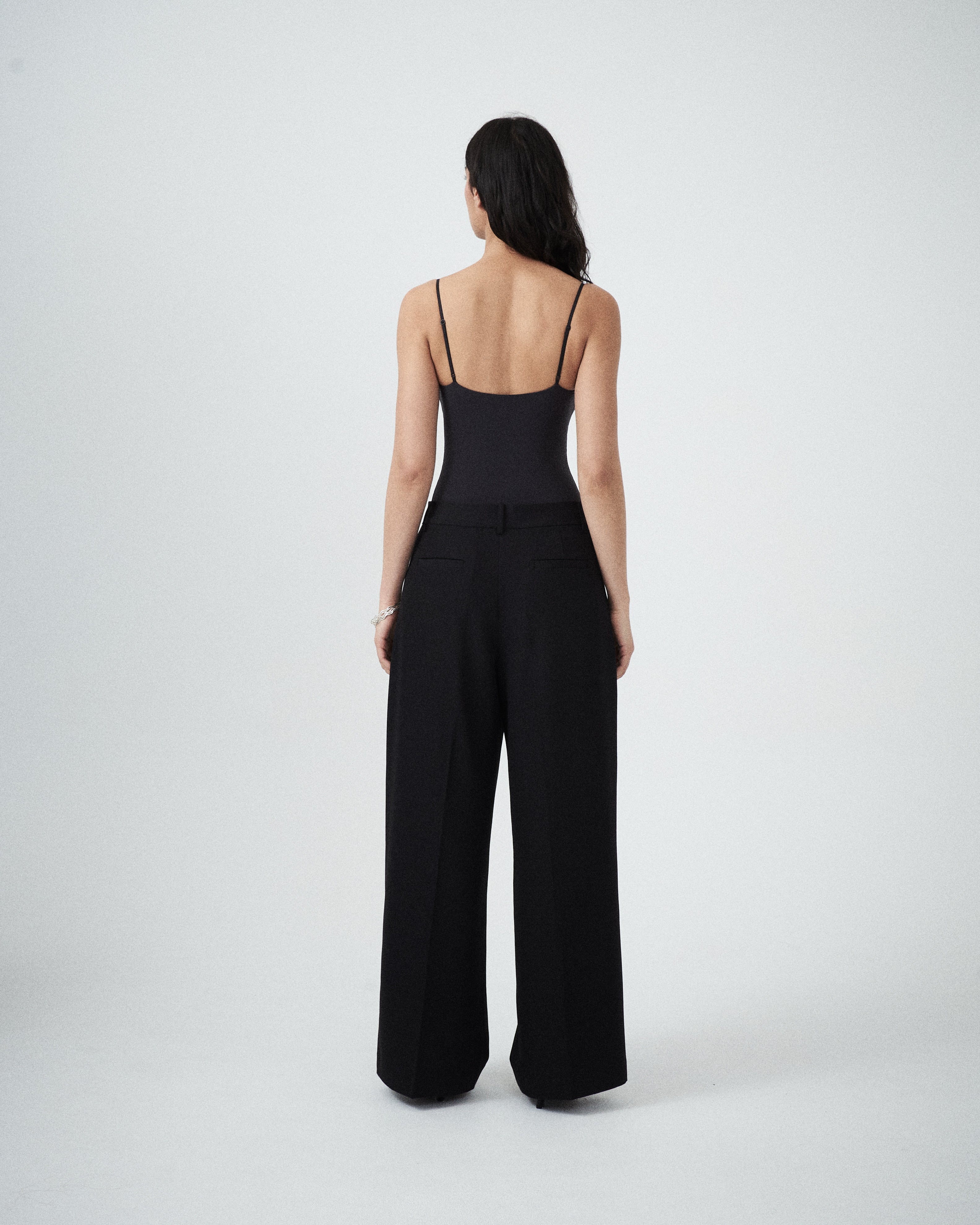 Back view of VARNA Enrica Relaxed Tailored Pant in black with straight leg and minimal tailoring.