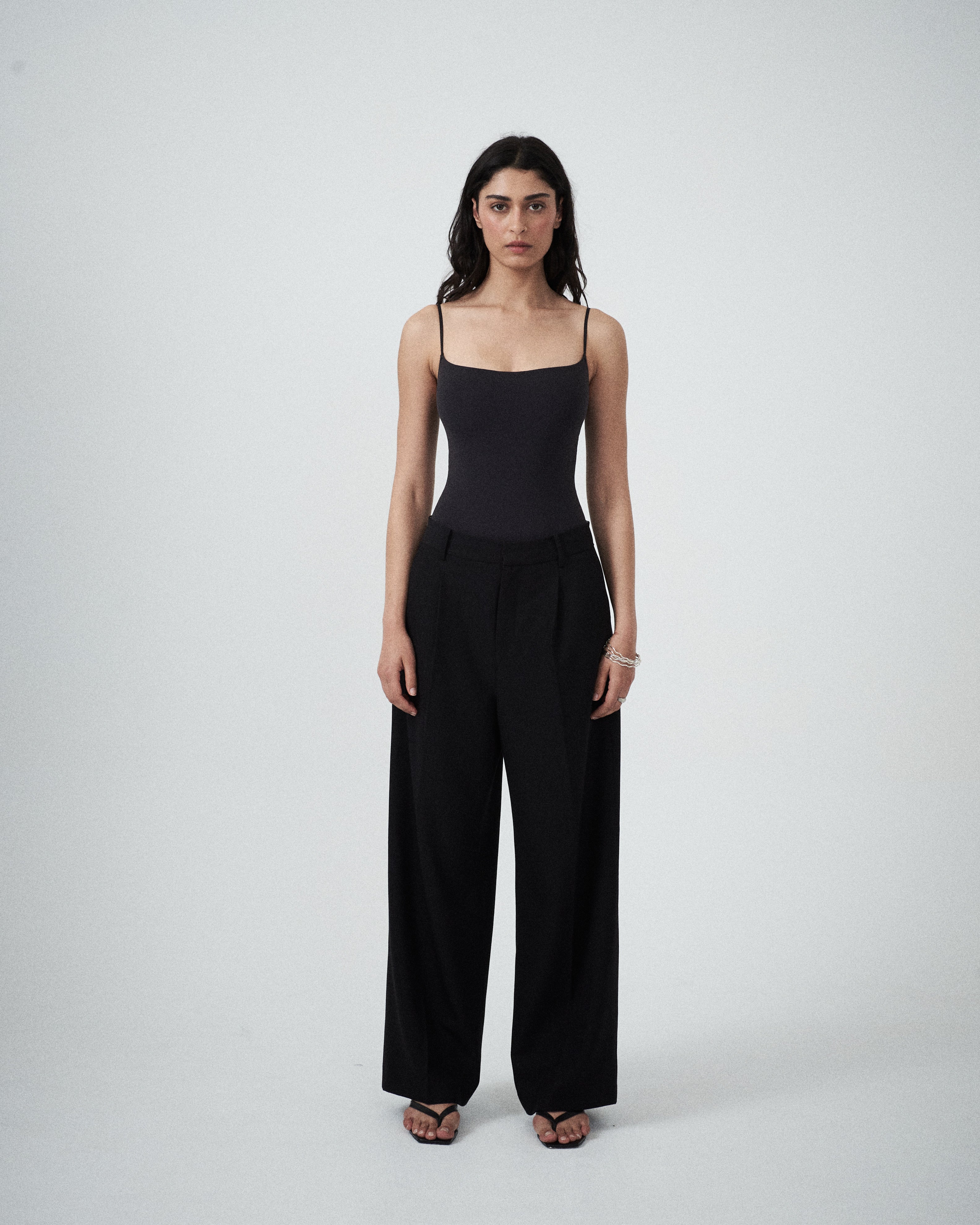 Front view of VARNA Enrica Relaxed Tailored Pant in black showing relaxed fit, front tucks, and clean waistband.