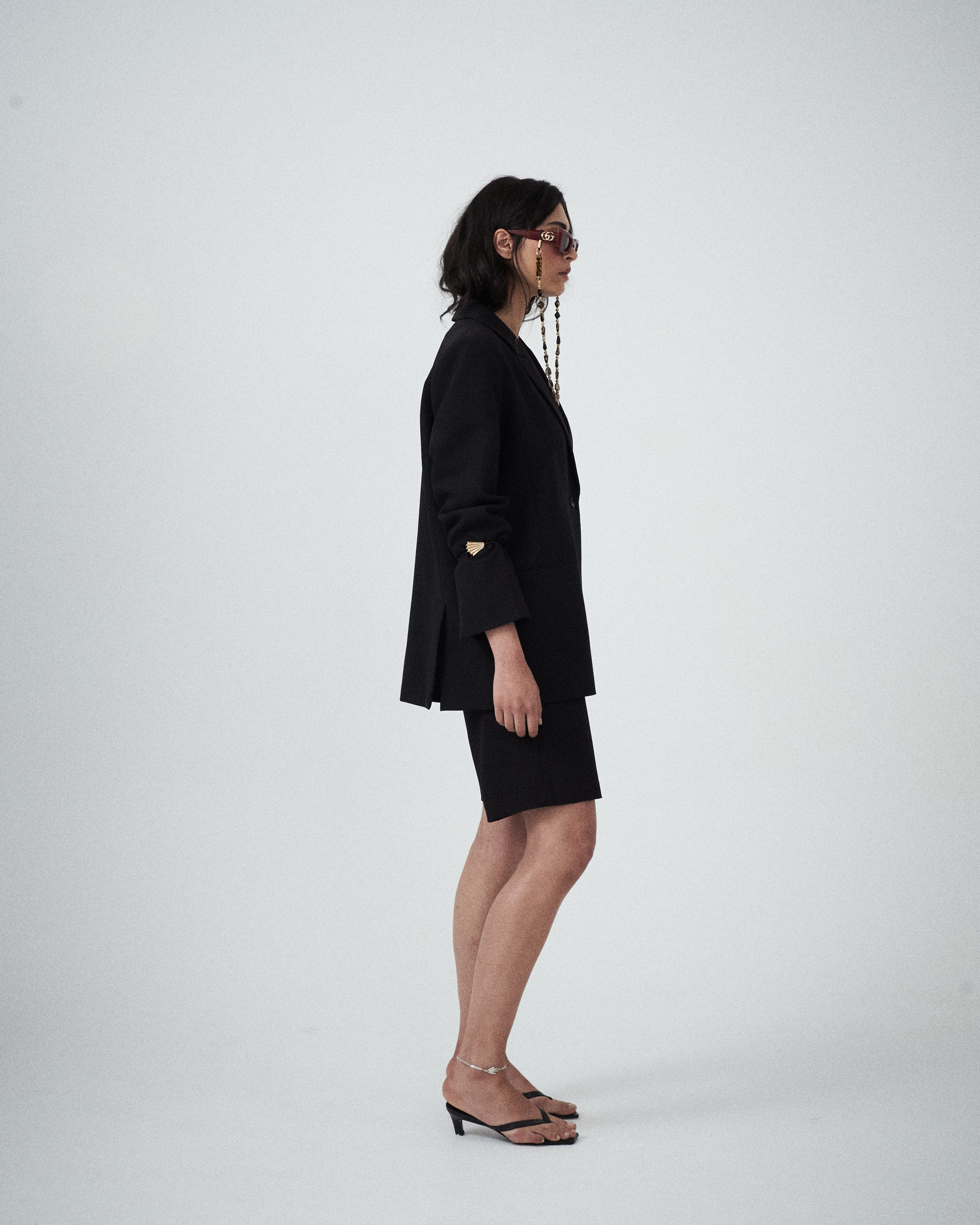 Side profile of VARNA Erica Oversized Blazer in black highlighting its fluid, oversized drape and clean tailored lines.