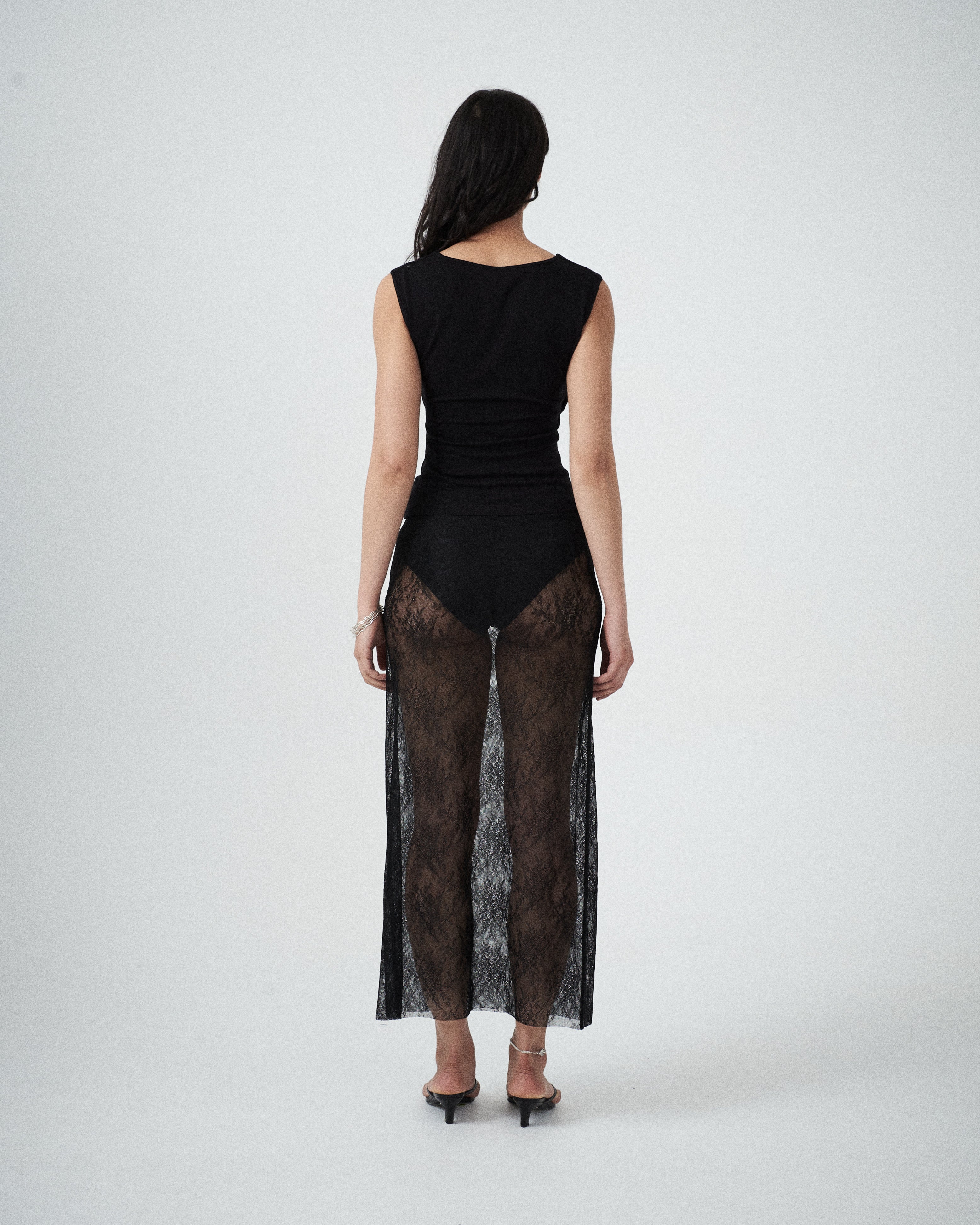 Back view of VARNA Lucienne Maxi Lace Skirt in black floral lace with sheer finish and refined scalloped detailing.
