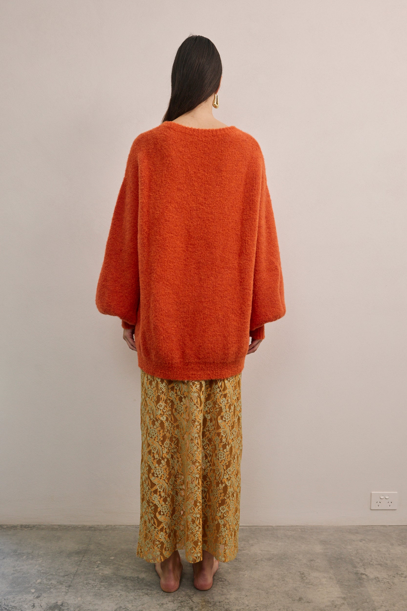 Back view of VARNA Lucienne Maxi Lace Skirt in tangerine lace highlighting elegant drape, scalloped hem, and delicate floral pattern.