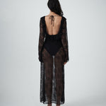 Back view of VARNA Lucienne Ruffle Lace Maxi Dress in black featuring open low back with tie and flowing lace train.