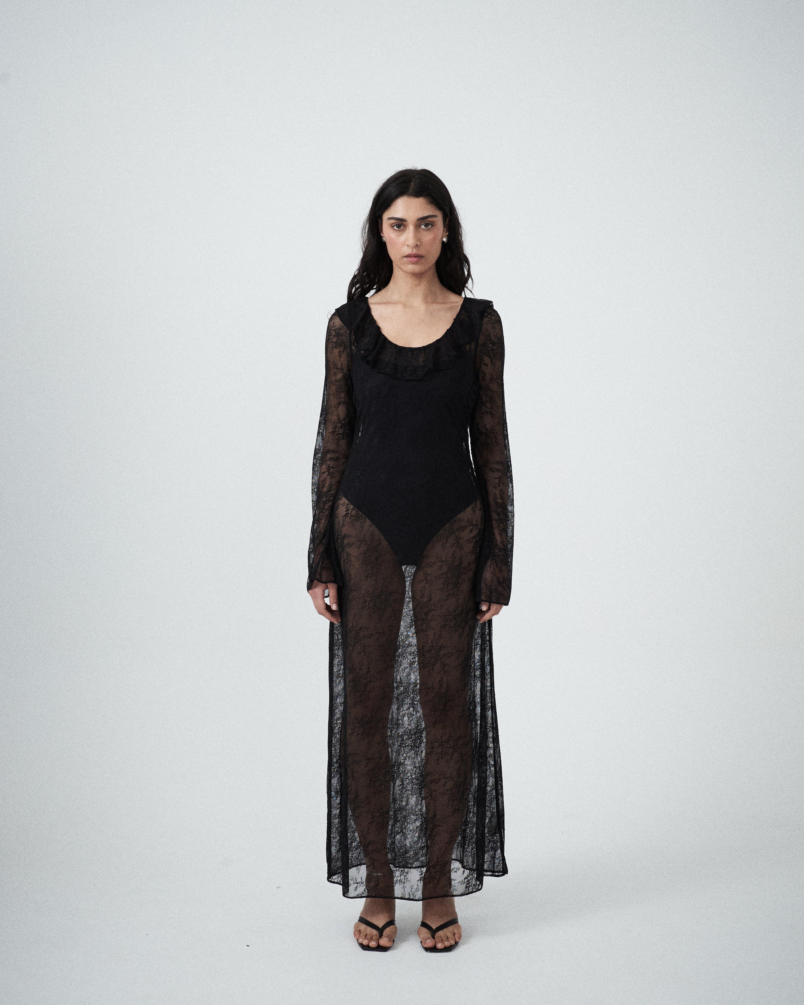 Front view of VARNA Lucienne Ruffle Lace Maxi Dress in black showing scoop neck, slim silhouette, and delicate ruffle hem.