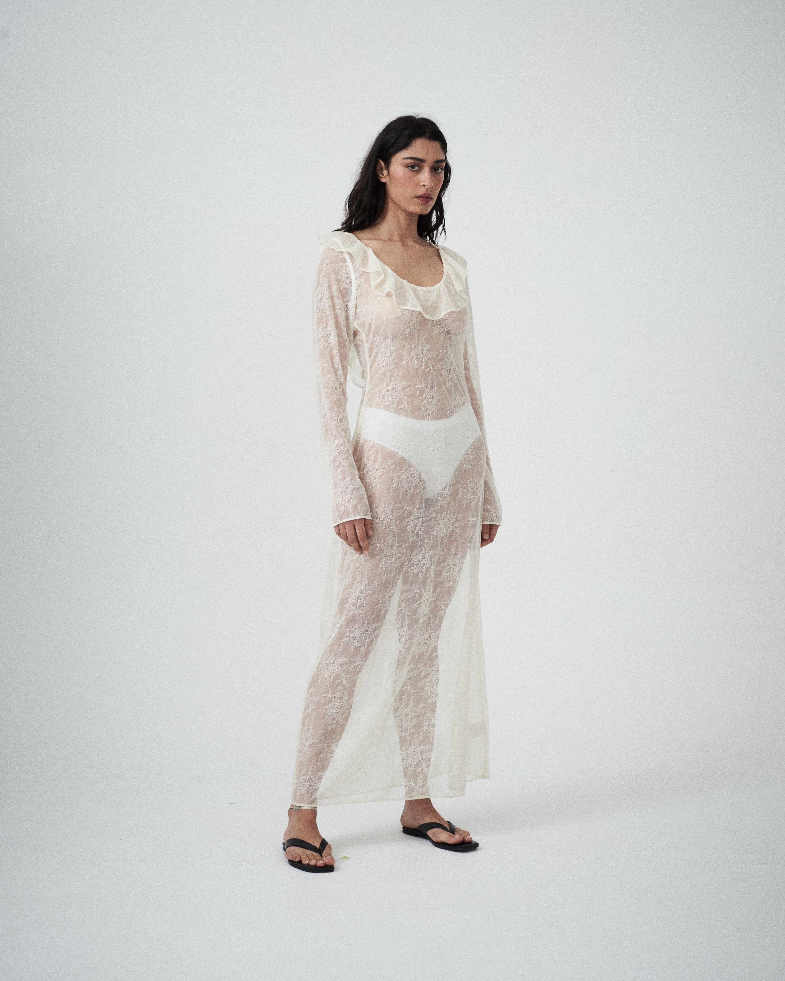 Three-quarter view of VARNA Lucienne Ruffle Lace Maxi Dress in milk showing low back tie, ruffled hem, and soft drape