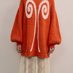 Front view of VARNA Maris Knit Top in tangerine alpaca-wool blend showing abstract motif and voluminous sleeves.