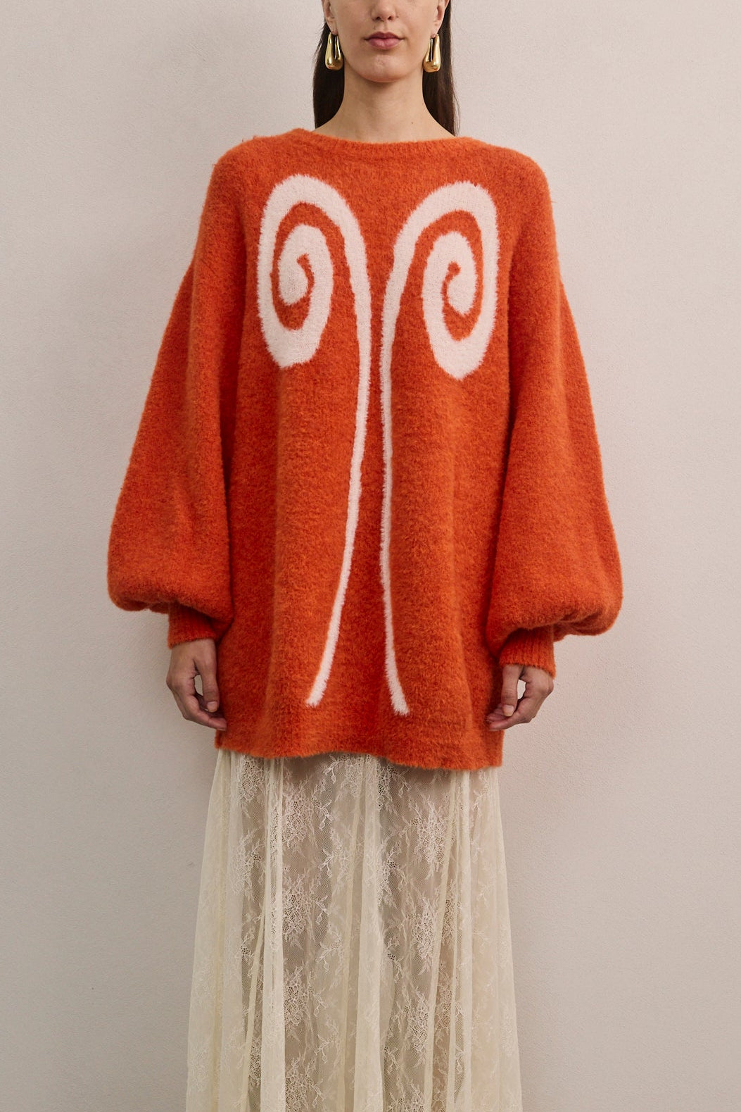 Front view of VARNA Maris Knit Top in tangerine alpaca-wool blend showing abstract motif and voluminous sleeves.