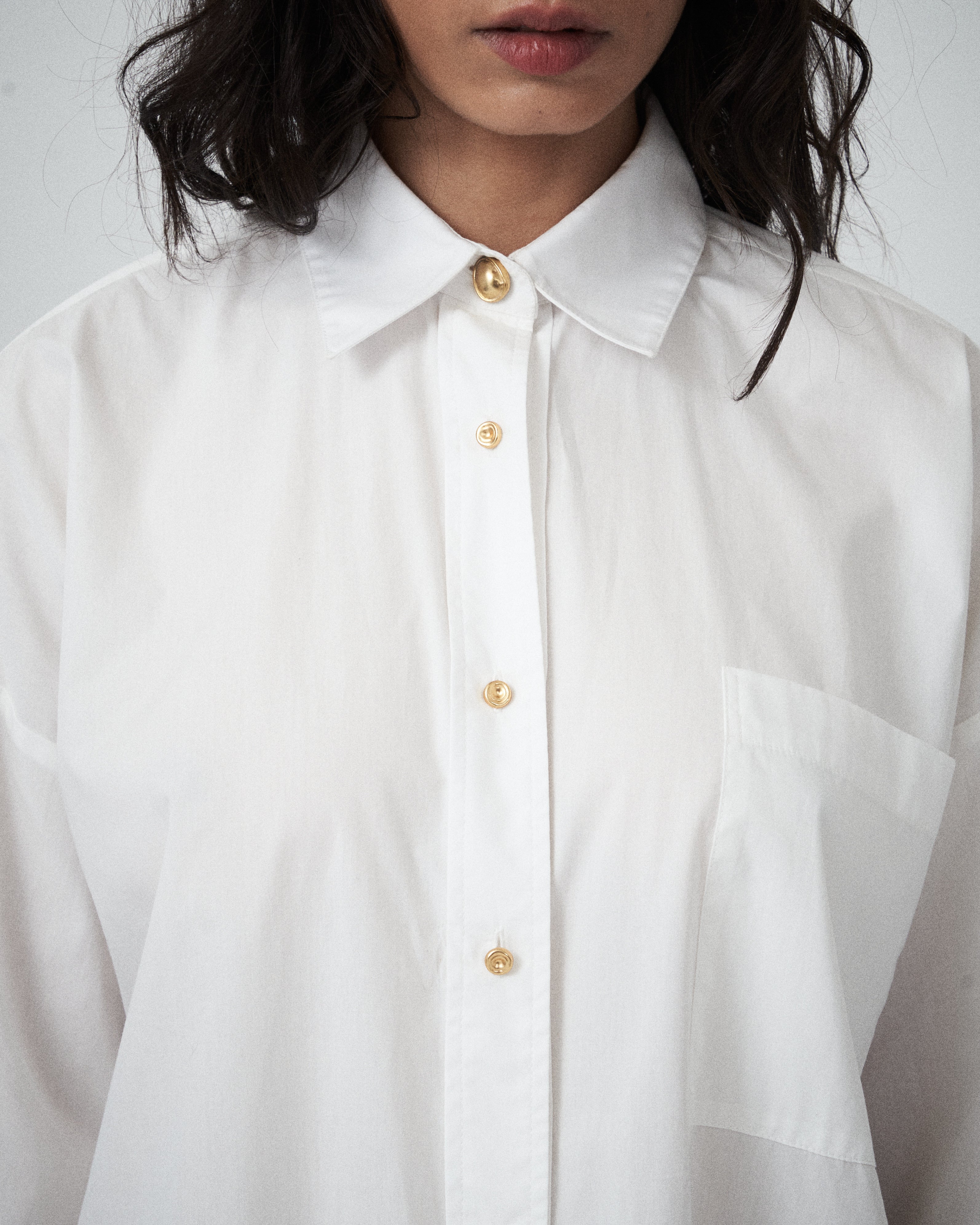 Detail view of VARNA Rhea Shirt showing crisp white cotton texture and front button placket.