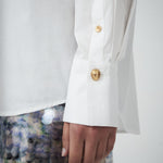Close-up of VARNA Rhea Shirt showing pleated cuff detail and gold-tone button on sleeve.