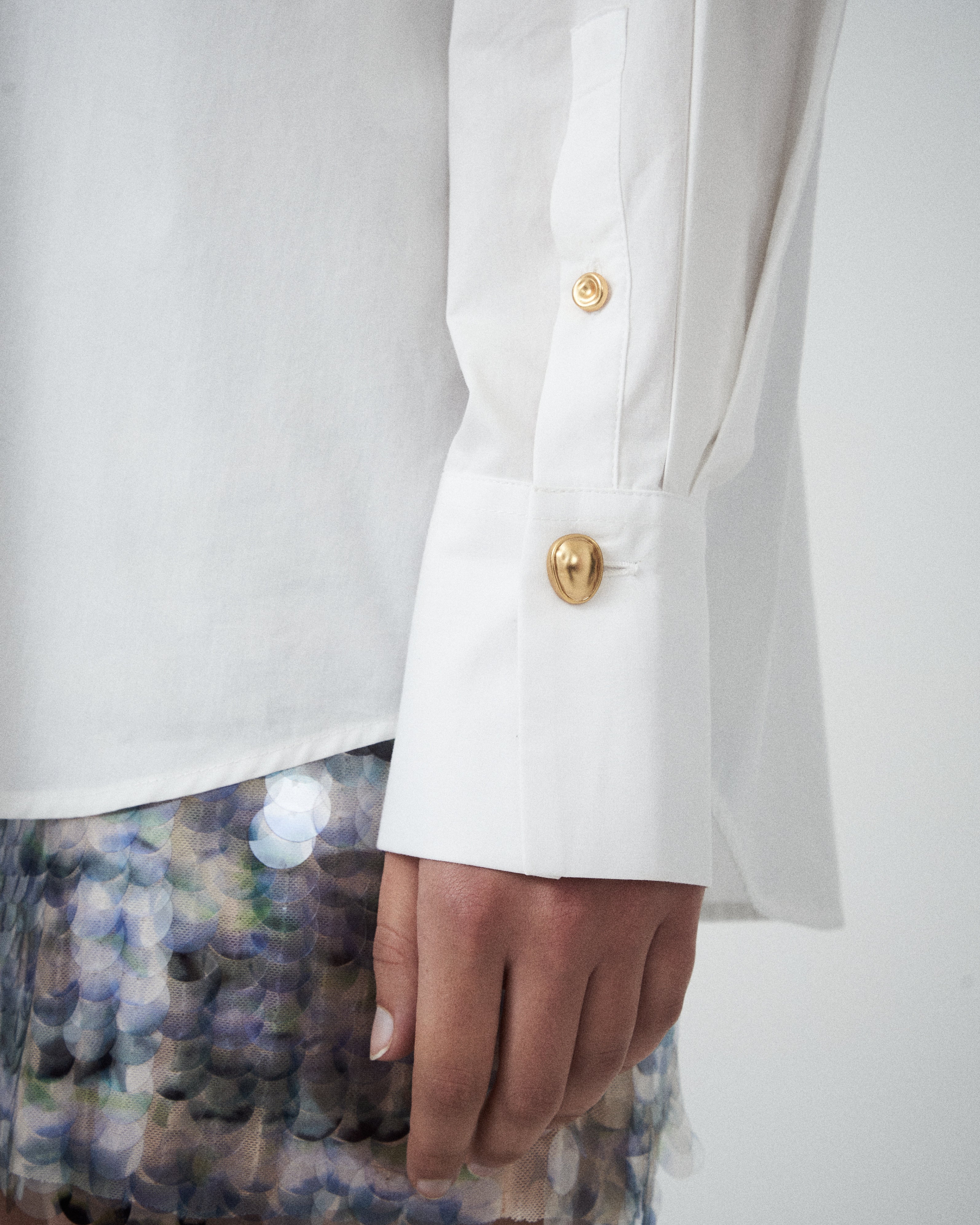 Close-up of VARNA Rhea Shirt showing pleated cuff detail and gold-tone button on sleeve.