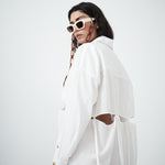 Crisp white cotton fabric of VARNA Rhea Tied Shirt with gold-tone buttons and tie details.